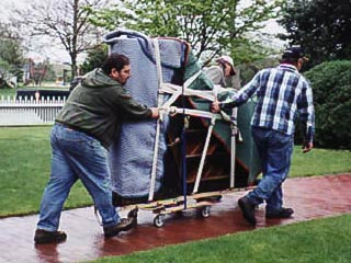 Jimmy Burgoff movers wheeling a blanket-wrapped piano on a dolly outside a home in Belchertown, Massachusetts
